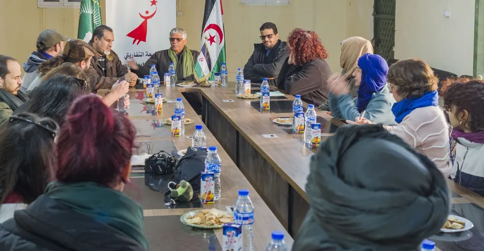 Reunión del grupo con anfitriones saharauis alrededor de una mesa larga