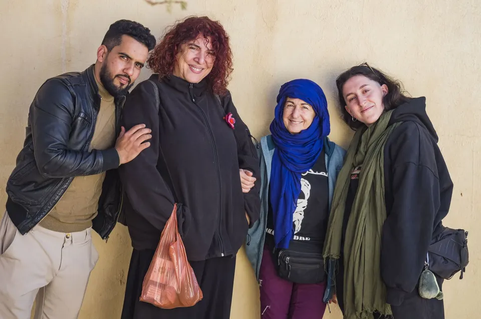 Cuatro personas de la expedición posan sonrientes contra una pared