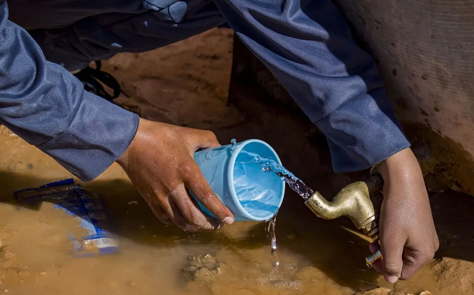 Agua que cae de un grifo a una taza azul